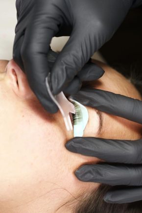 Close-up of a woman getting eyelash extensions by a beautician. Using tweezers, the extensions are applied to her natural lashes. Her eyes closed in relaxation during the painless two-hour procedure.